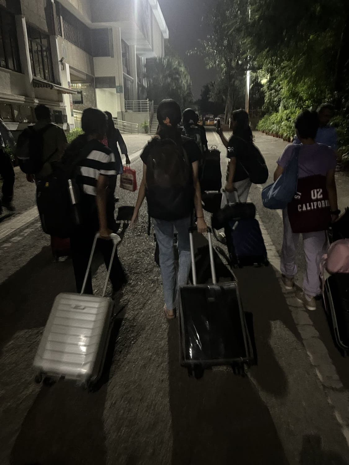 Wheeling suitcases along a road at night, arriving