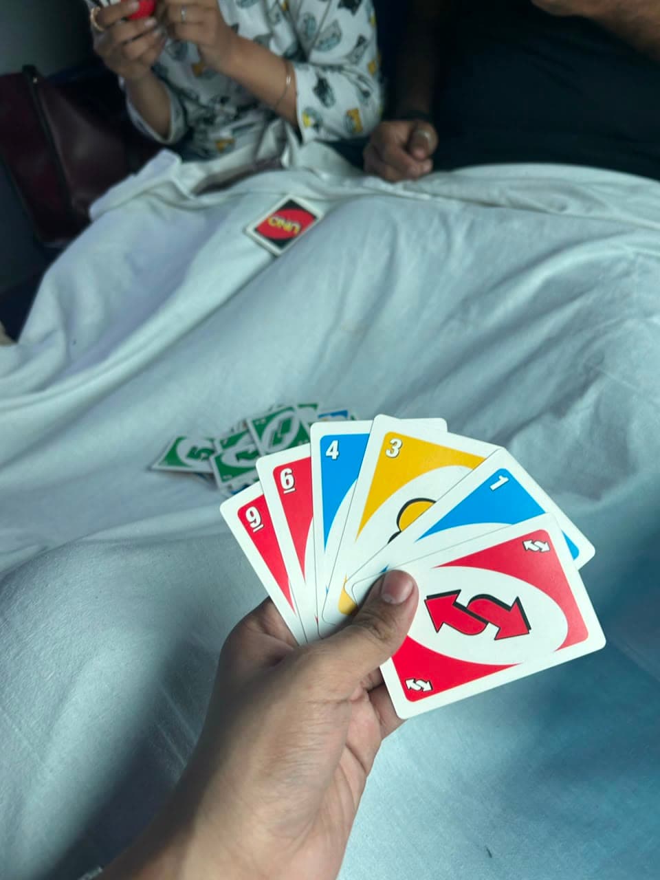 A hand of UNO cards on a train berth, mid-game