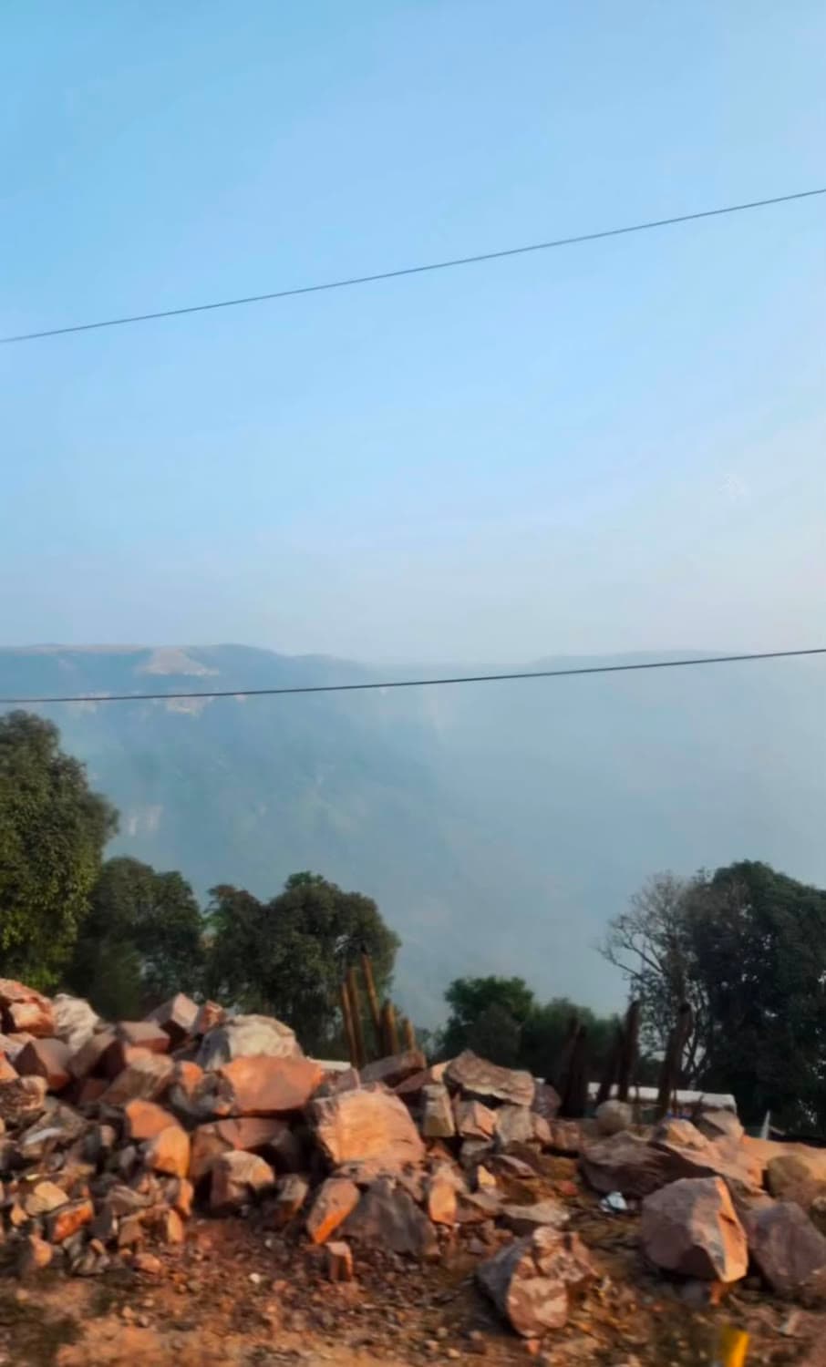 A hazy valley seen from a rocky ridge