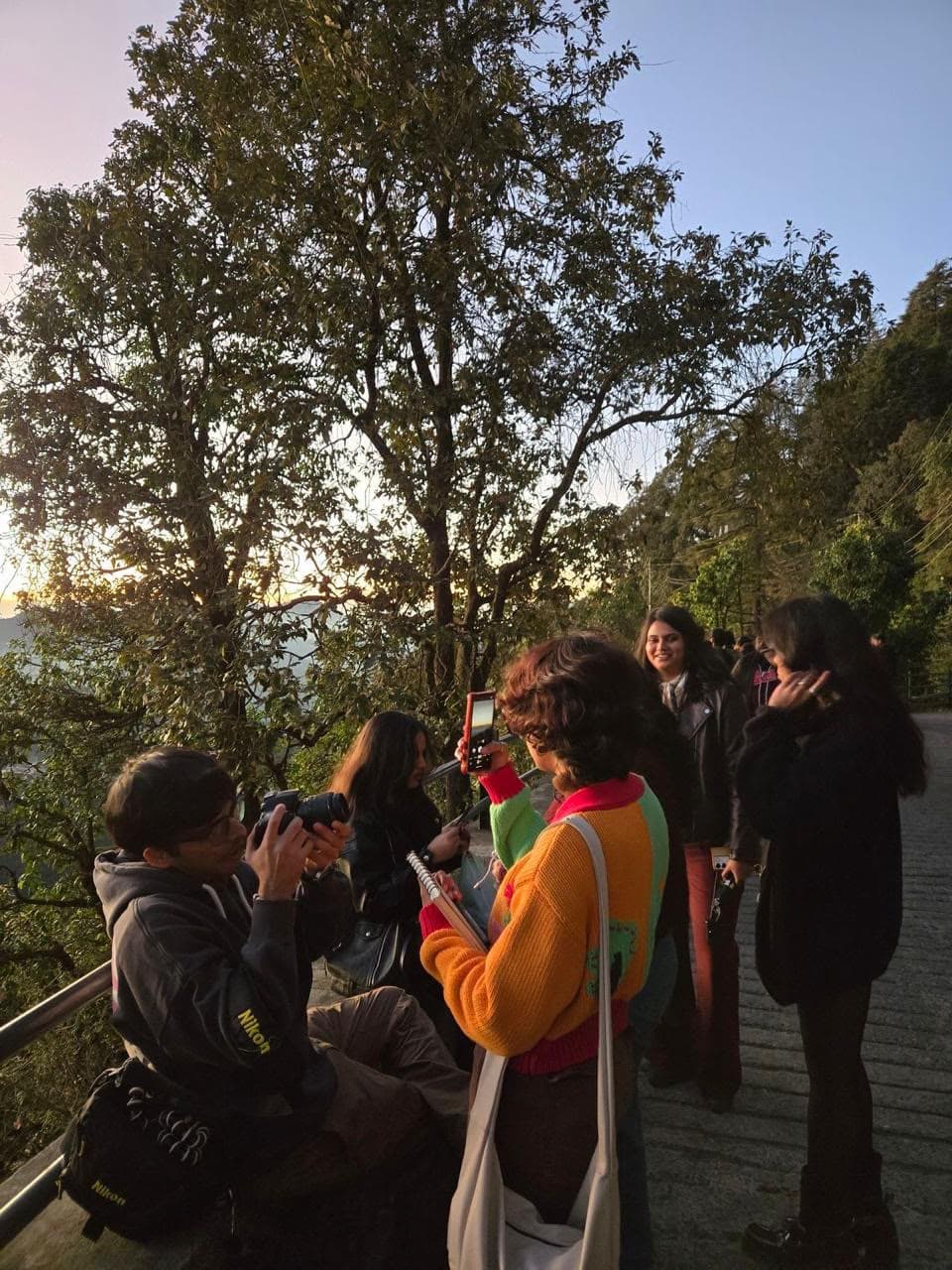 A group at a hill viewpoint at golden hour, cameras out
