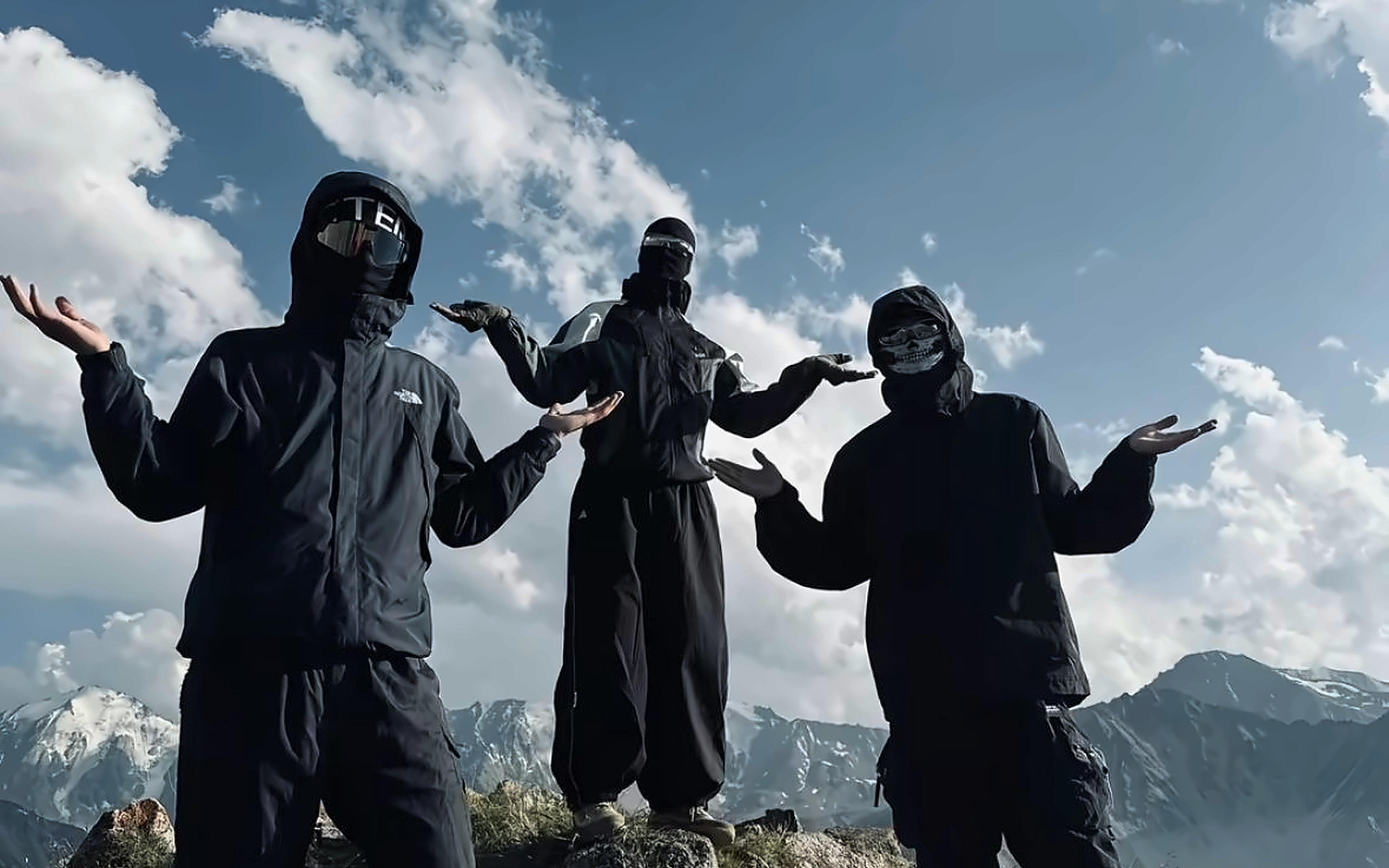 Three friends in masks shrugging on a mountain top