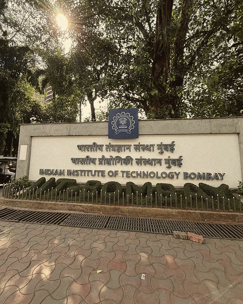 The IIT Bombay sign at the main gate, under the trees