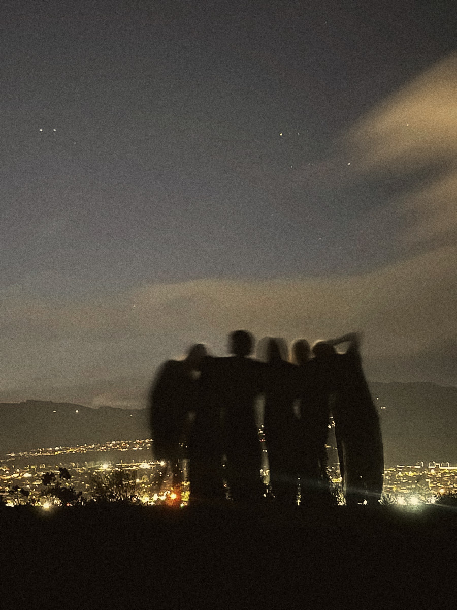 Friends arm in arm on a hilltop at night