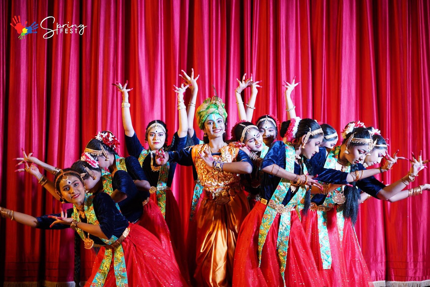 A classical dance troupe in full costume on stage