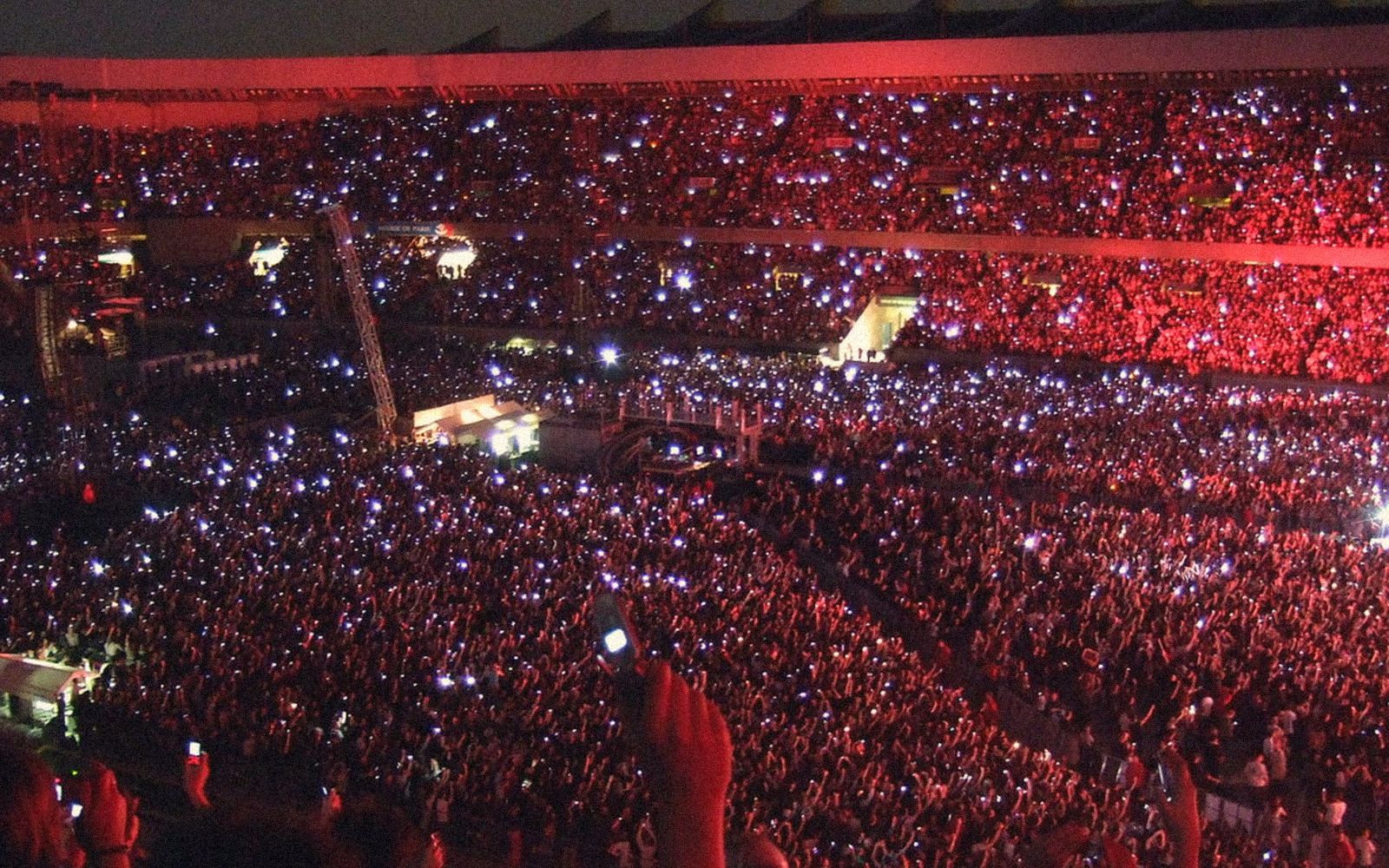 A stadium crowd lit up with phone lights