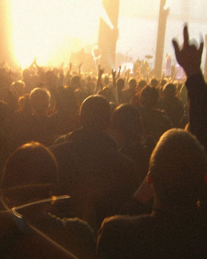 A crowd with hands up in front of a bright stage