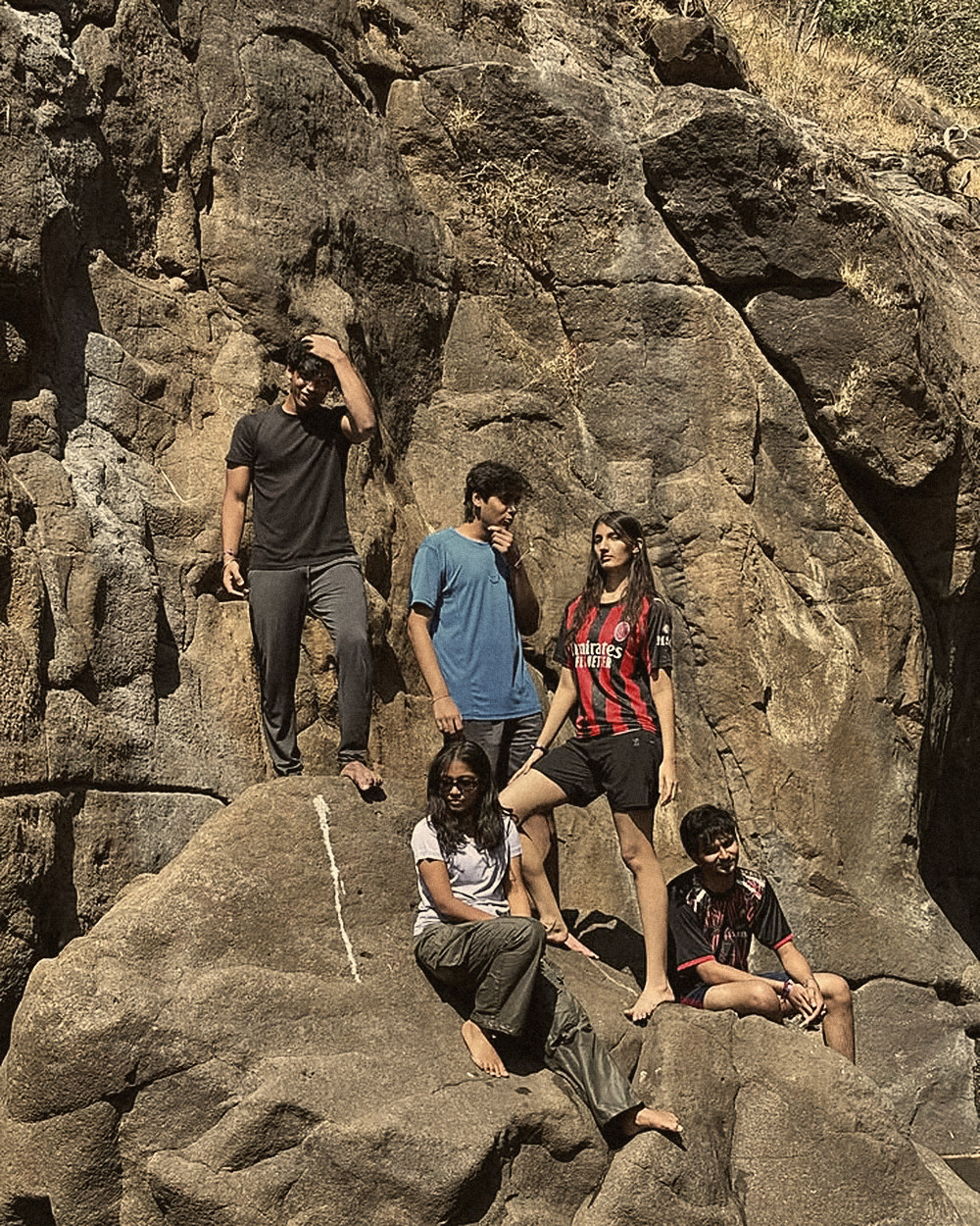 Friends posing on a rock face in the sun